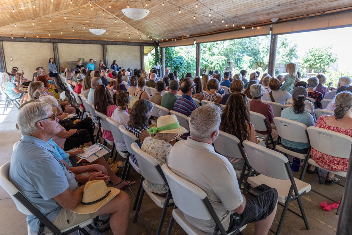 Guests gathered together outdoors under the shade at a community event