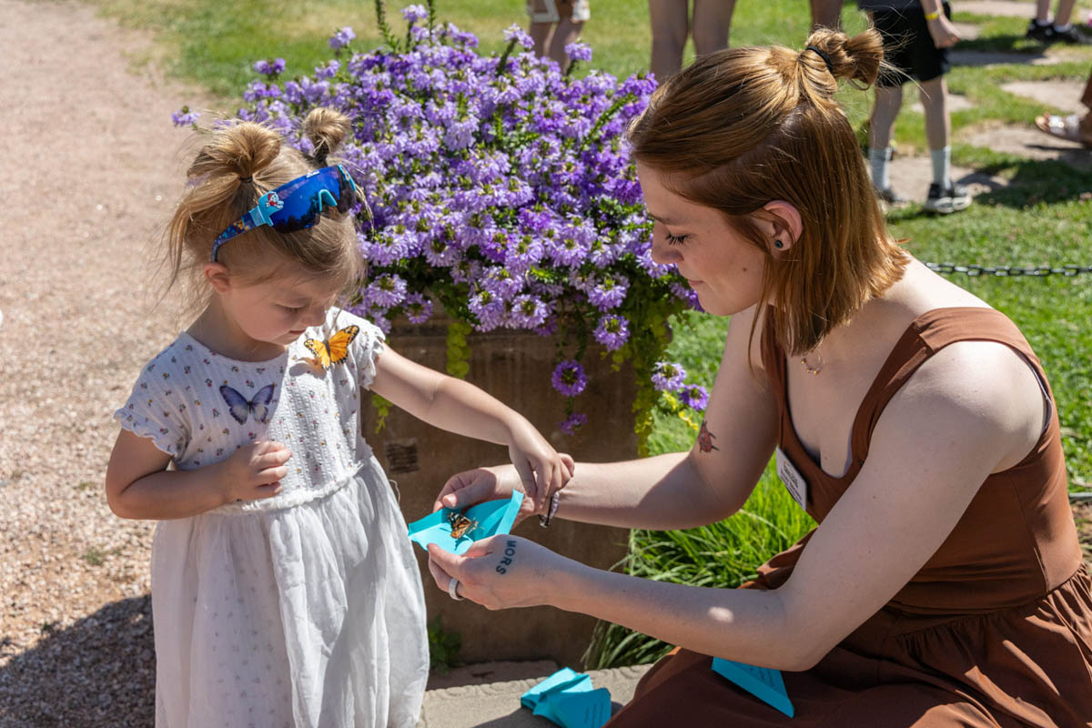 Young participants planting flowers alongside a volunteer